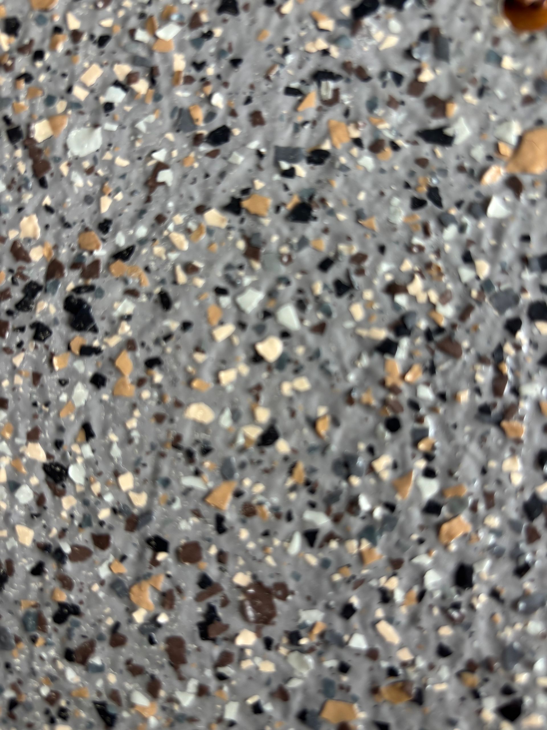 Gros plan sur une surface grise mouchetée avec de petits éclats de couleurs variées comme le blanc, le noir et le beige.
