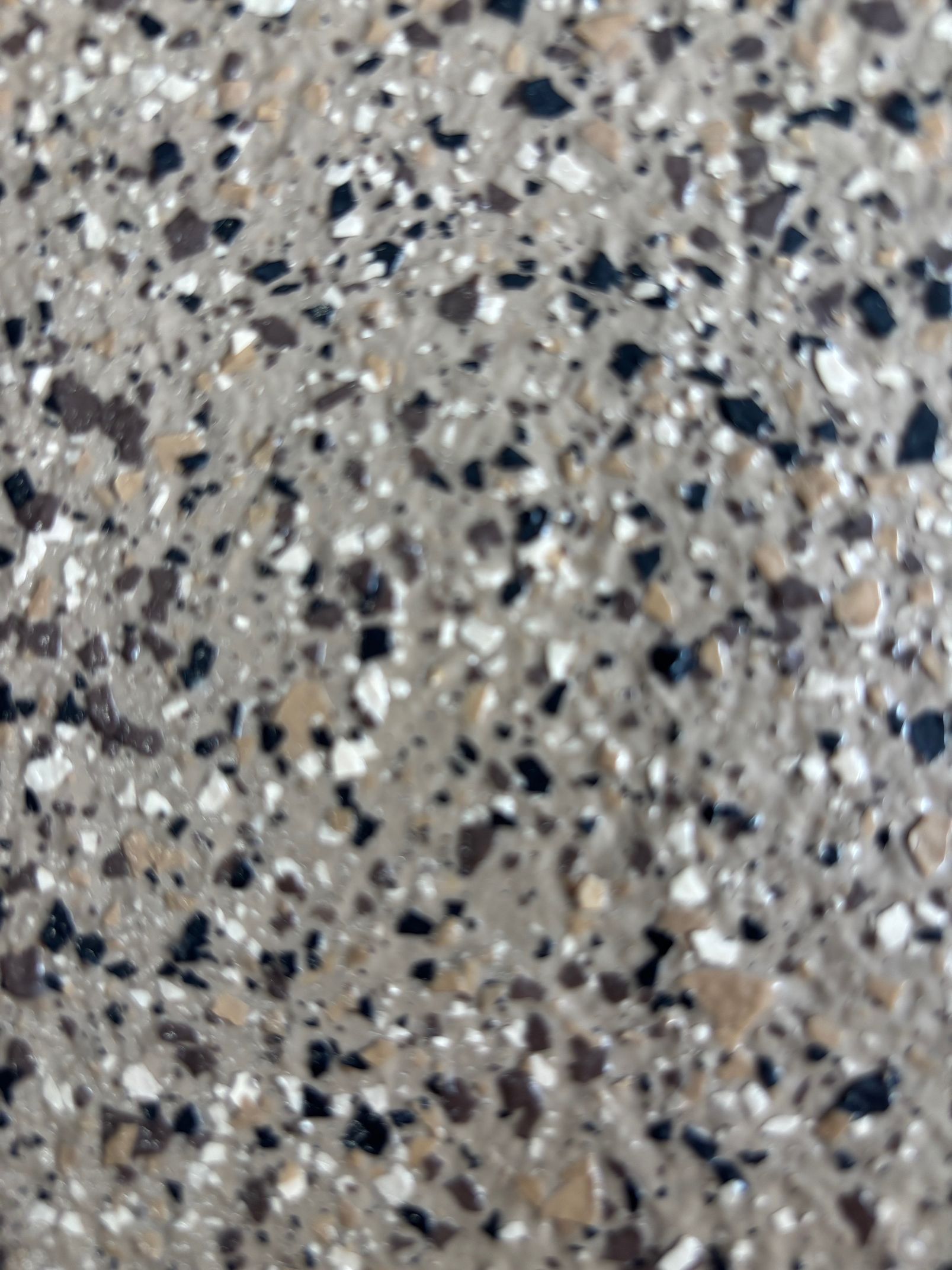 Gros plan sur une surface en béton moucheté ; nuances de gris, de noir, de beige et de blanc.