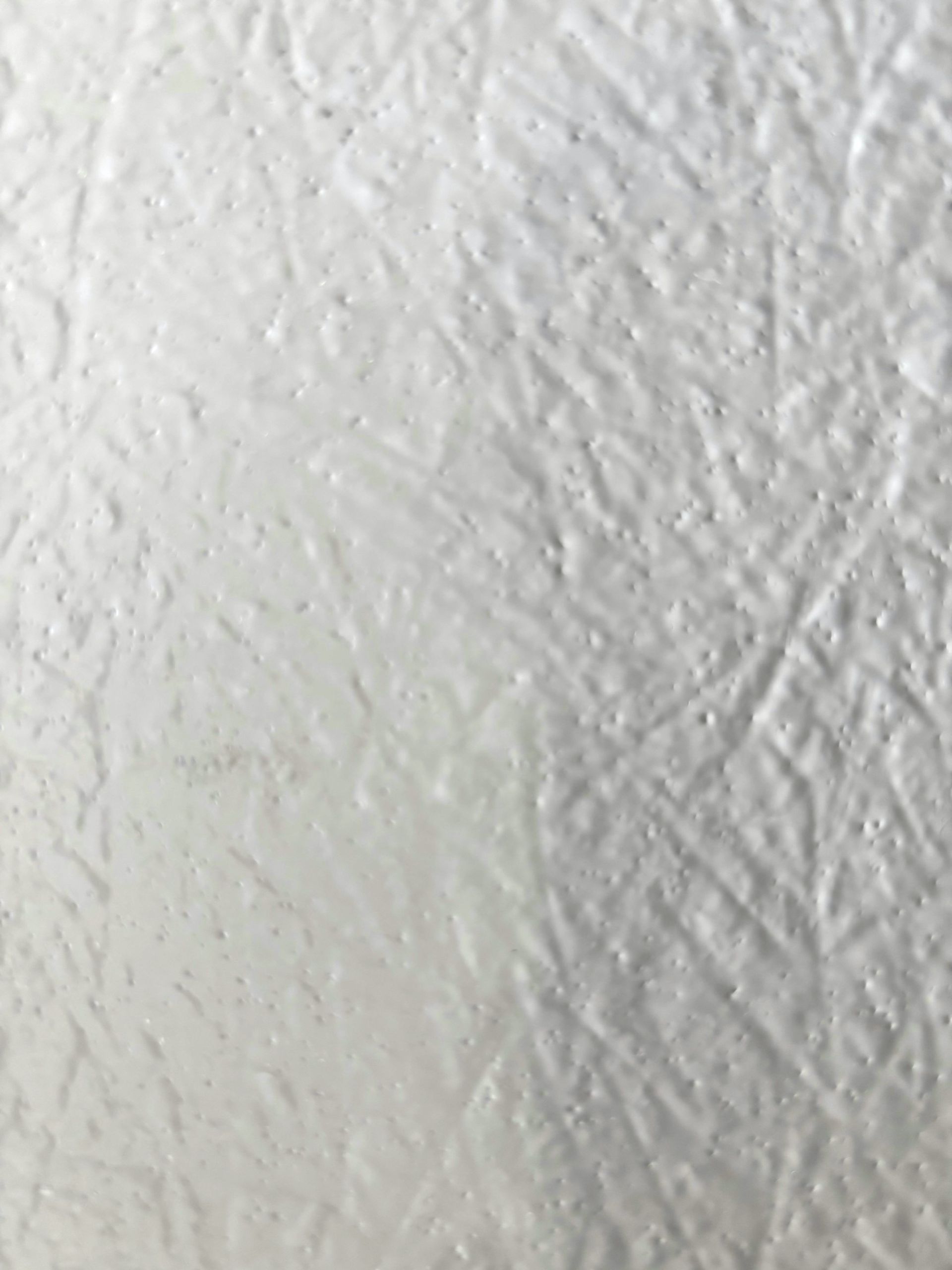 Gros plan sur une surface blanche texturée présentant des lignes visibles et des nuances variées, probablement de la peinture ou du tissu.