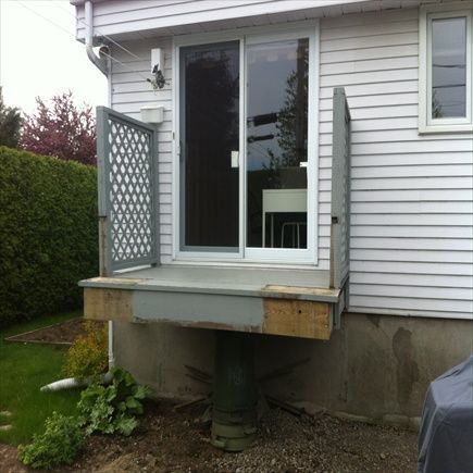 Une plateforme surélevée en bois avec une porte coulissante en verre et un panneau latéral décoratif.