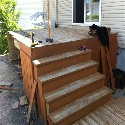 Terrasse et escalier en bois en construction à côté d'une maison avec fenêtre. Outils de chantier visibles.