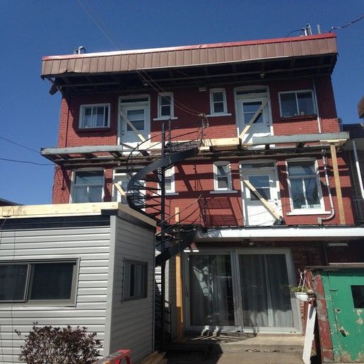 Bâtiment en briques avec escalier en colimaçon, en cours de rénovation ; échafaudages et supports de construction visibles.