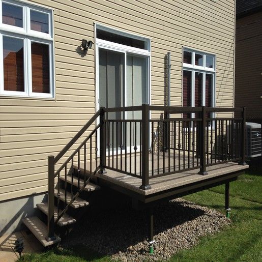 Maison à l'extérieur beige avec une petite terrasse et un escalier ; balustrade marron.