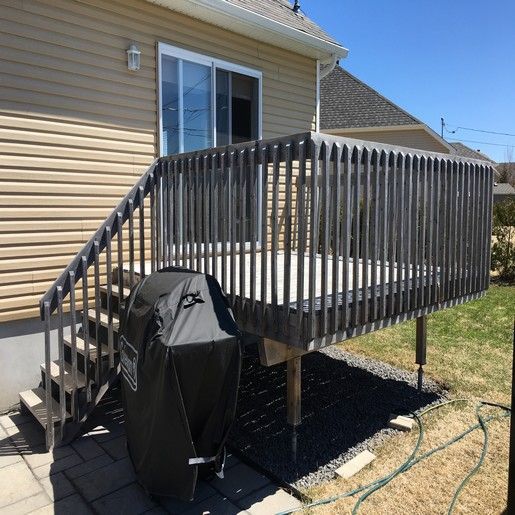 Terrasse en bois avec escalier, barbecue couvert et bardage beige sur la maison.