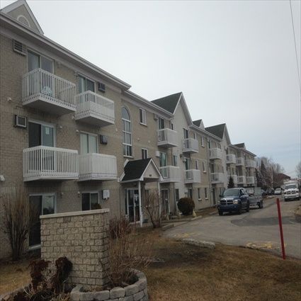 Immeuble d'appartements avec balcons et allée carrossable par temps couvert.