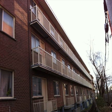 Immeuble d'appartements en briques avec balcons, balustrade grise.