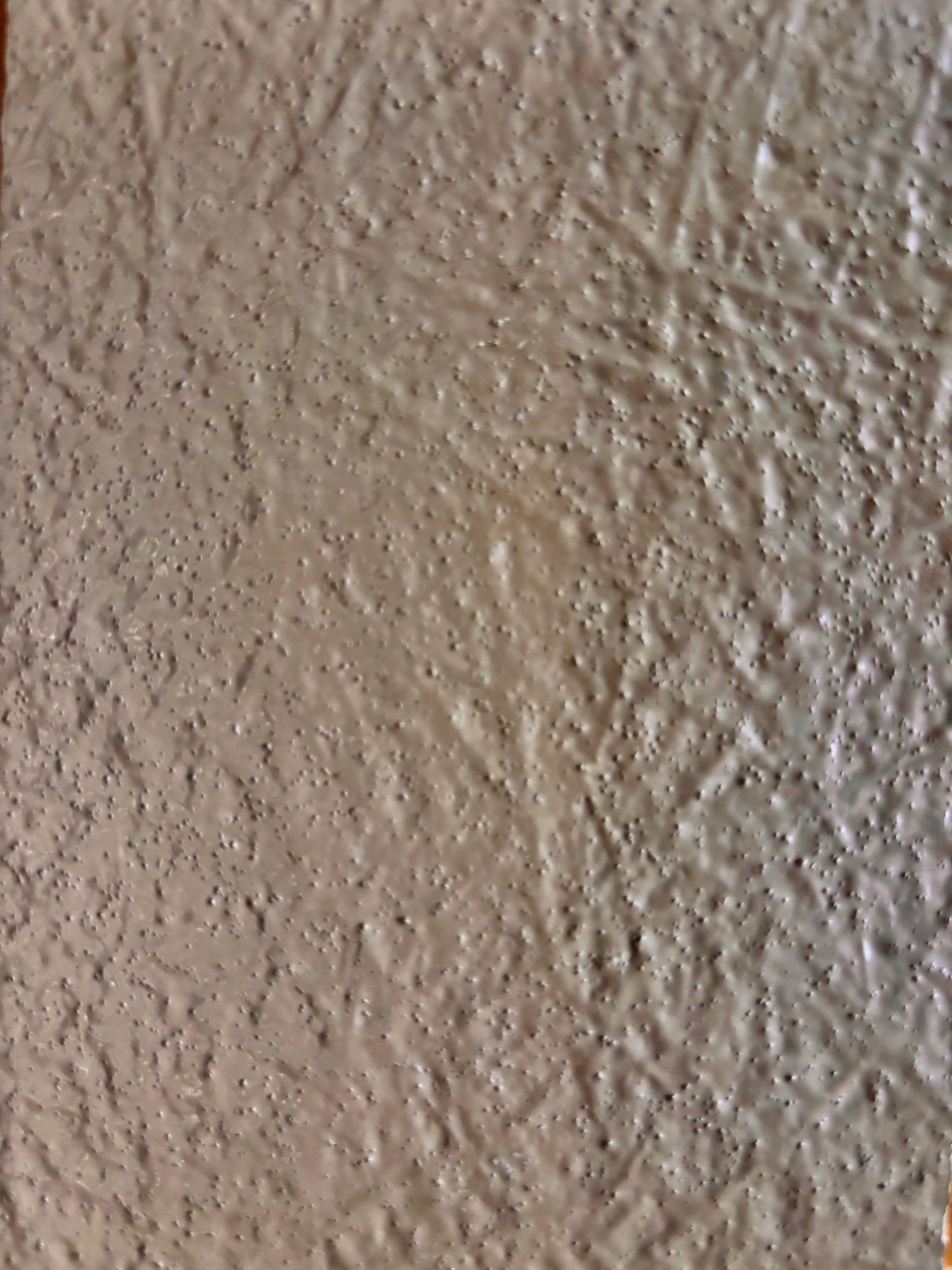 Mur beige texturé à la surface rugueuse et légèrement irrégulière.