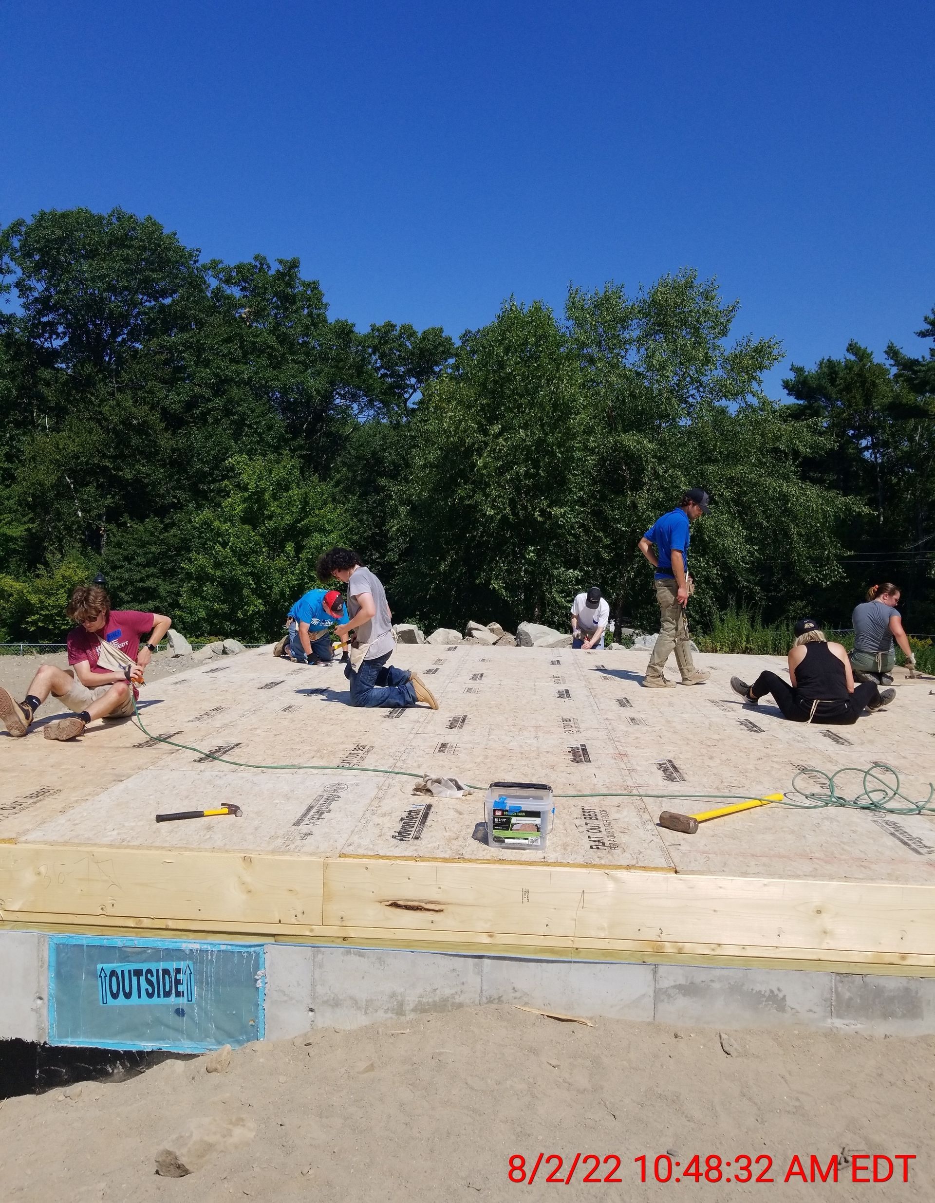 A group of people are working on a sandy area with a sign that says