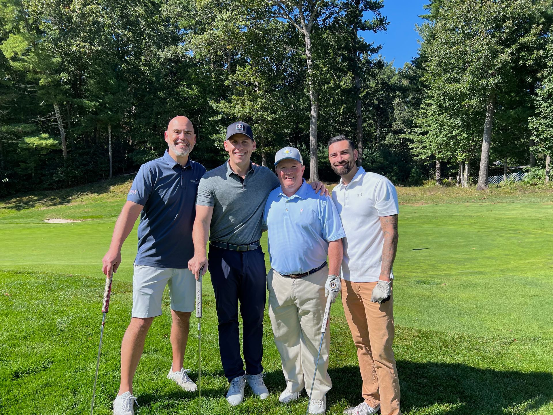 Four men are posing for a picture on a golf course