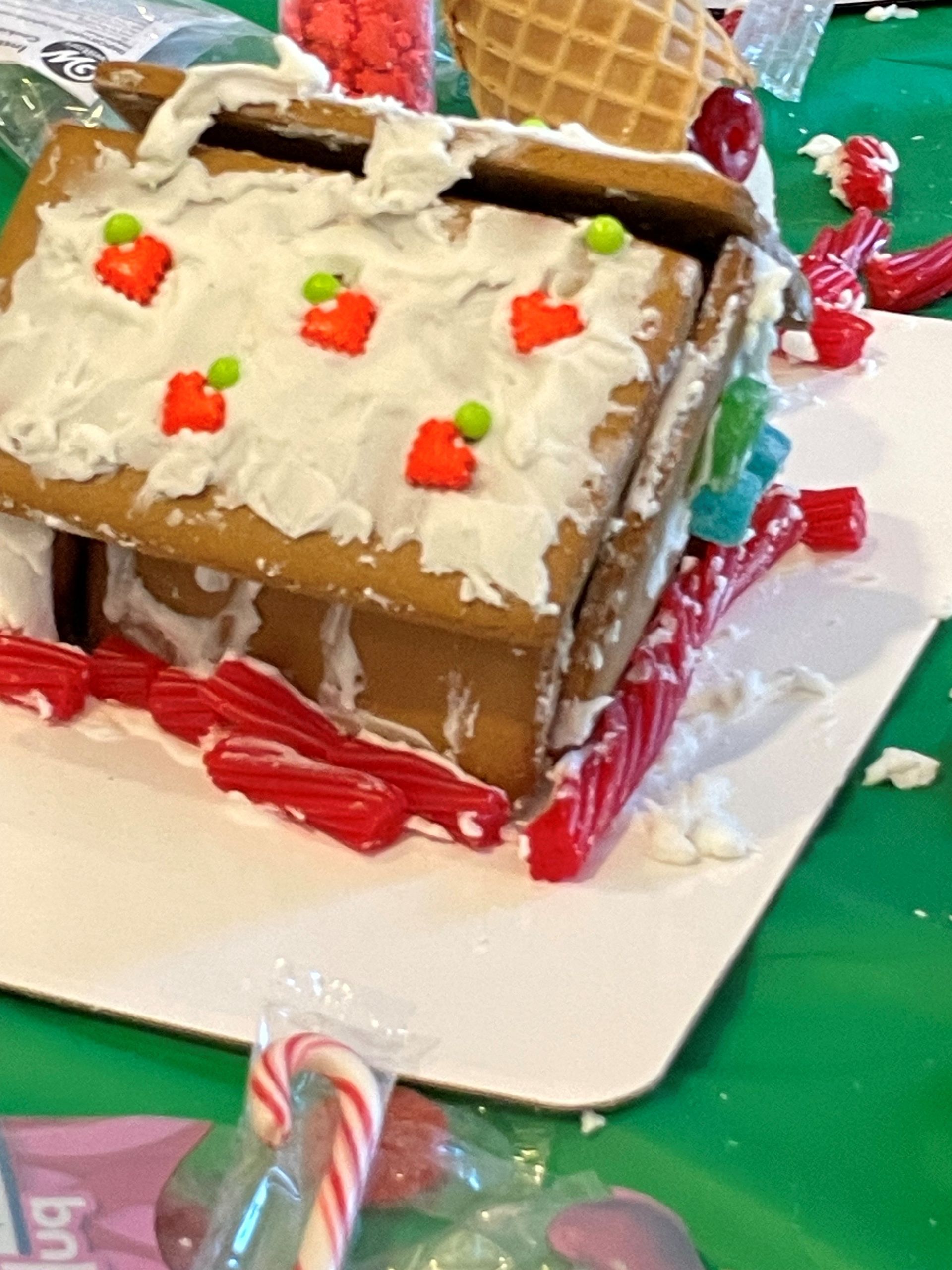 A gingerbread house is sitting on a white plate on a table