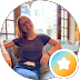 Person sitting at a wooden table, smiling beside a warm lamp and window, with a star badge icon overlay.
