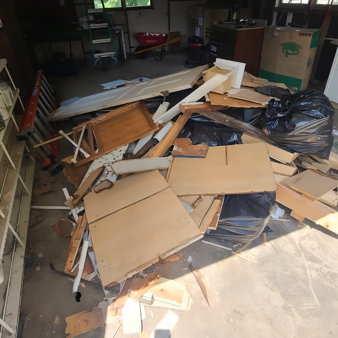 Garage floor piled with broken cardboard, wood, and black trash bags in messy debris.