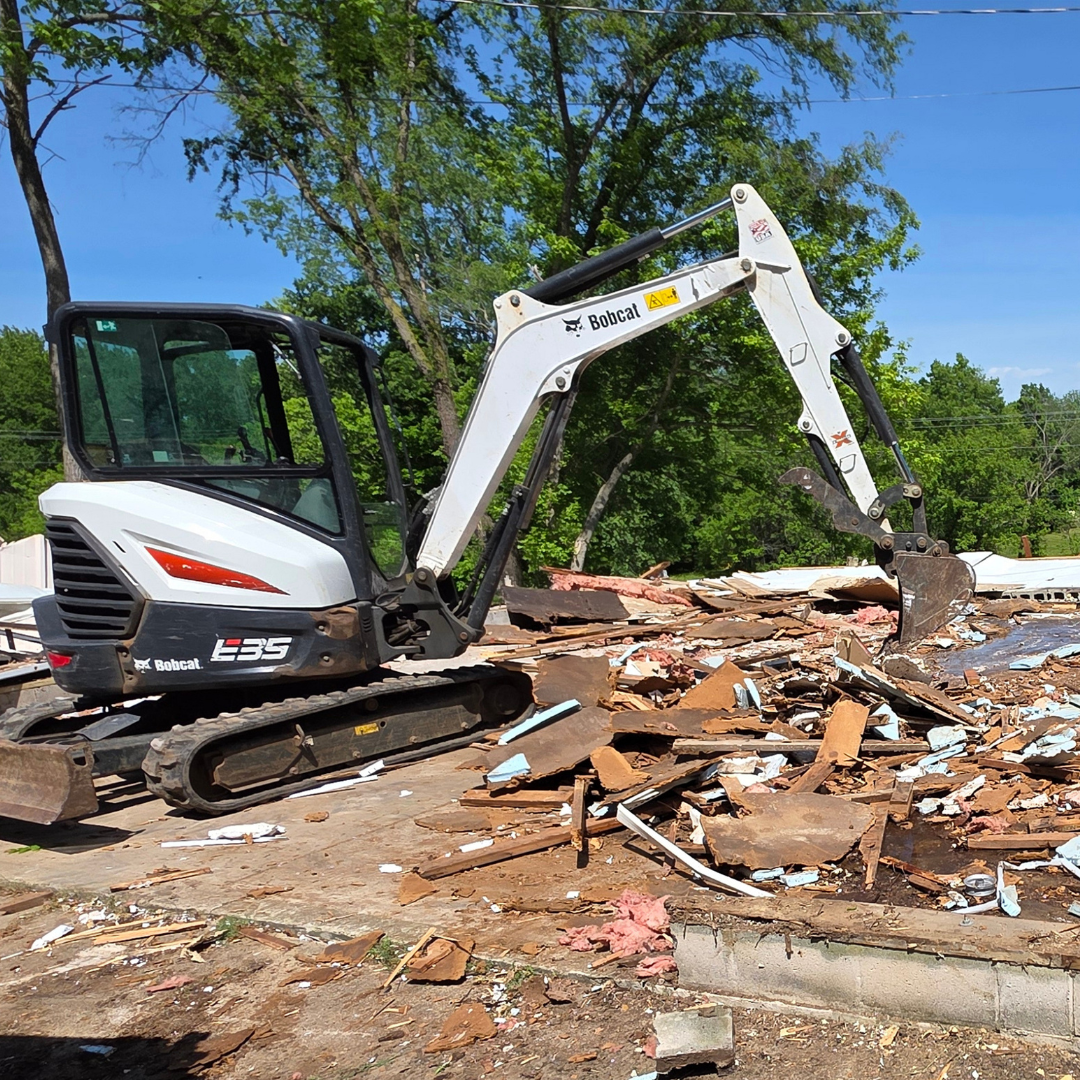 White excavator demolishing rubble on a sunny construction site
