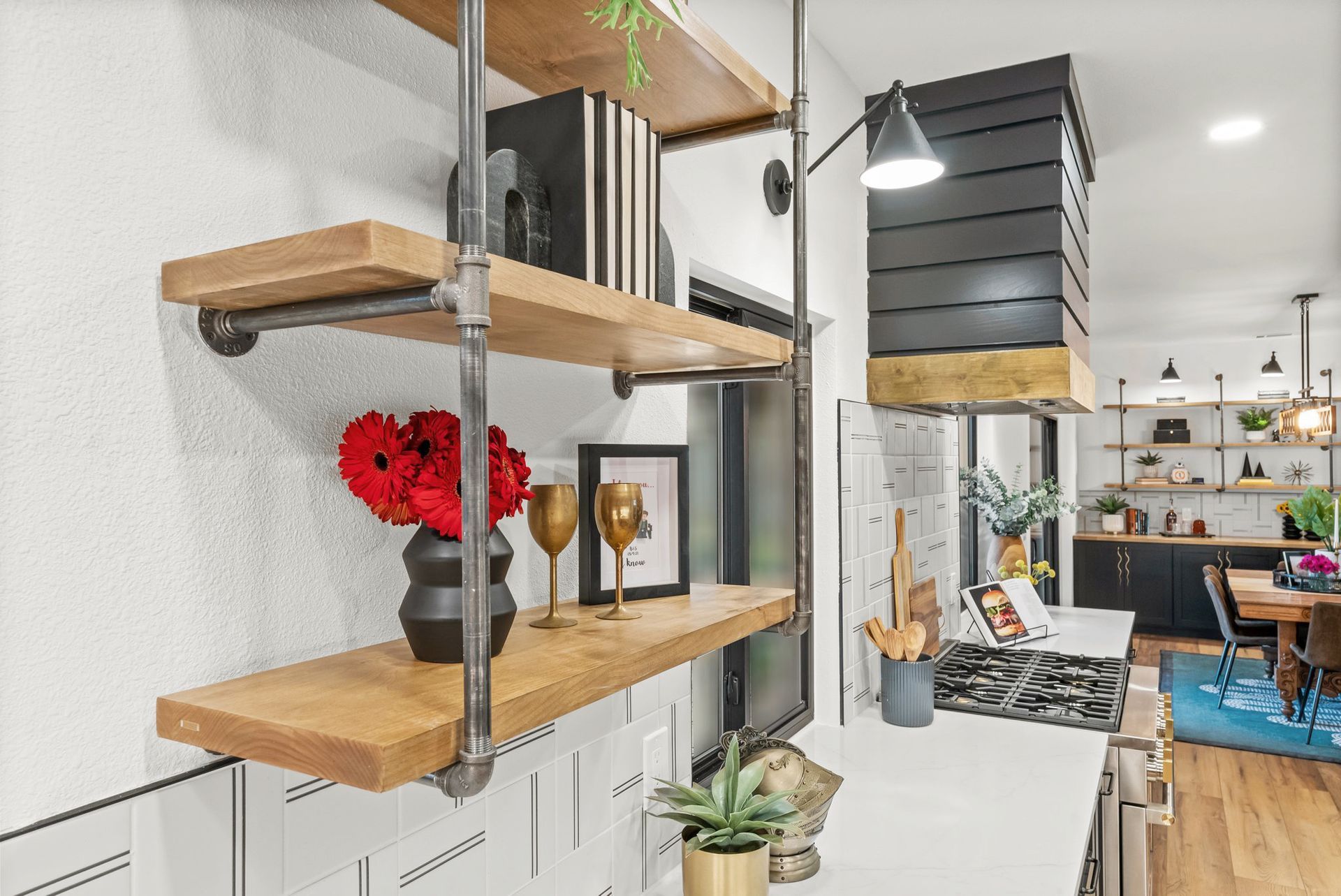 Modern open kitchen and hallway with floating wood shelves, black accents, and decor