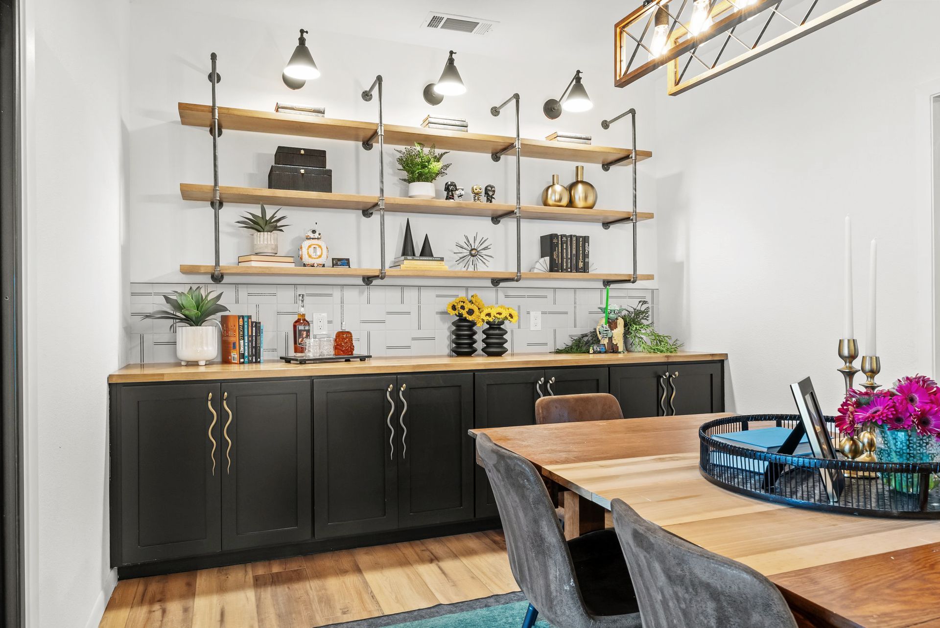 Modern dining room with wooden table, black sideboard, open shelving, and hanging pendant lights