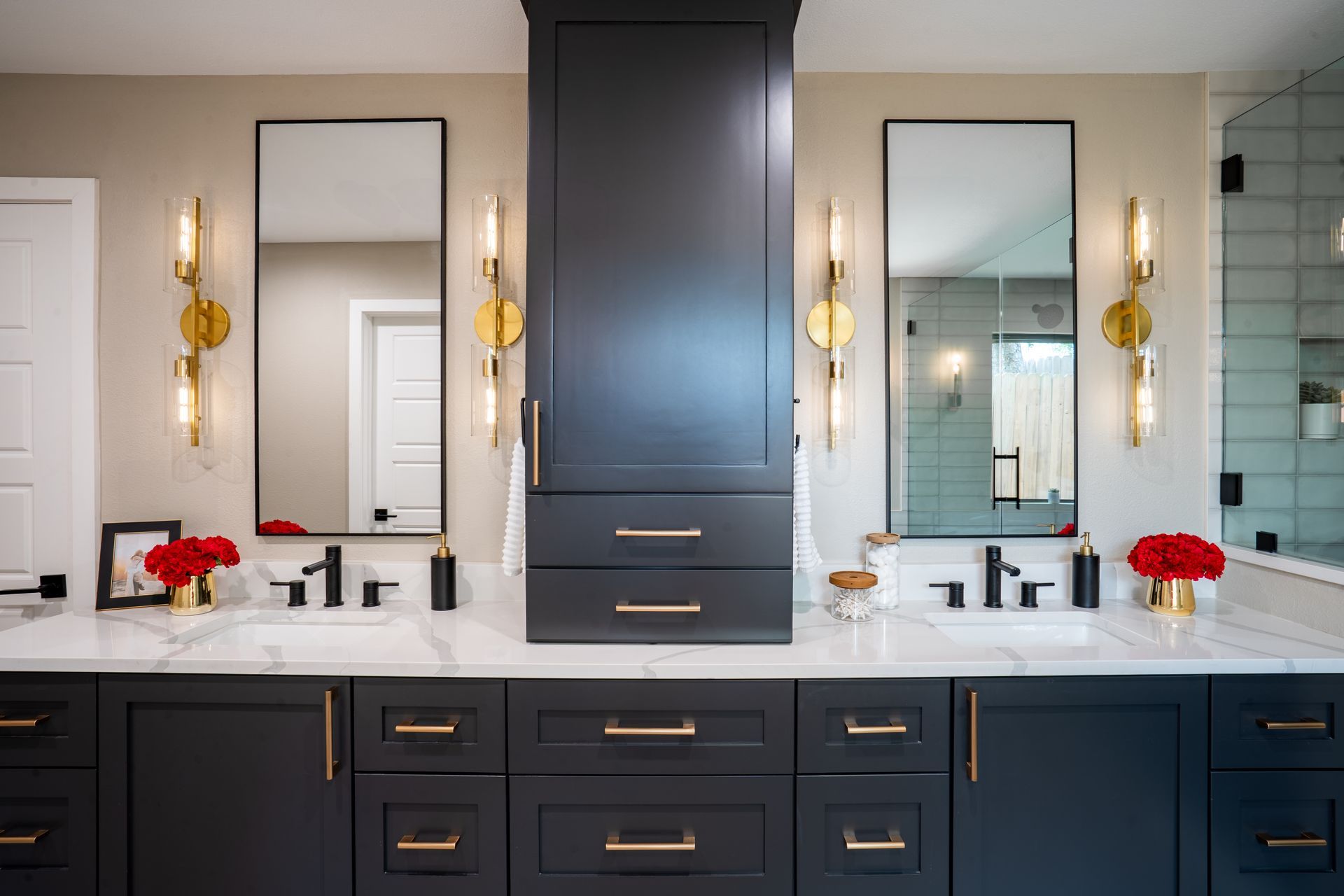 Elegant double vanity bathroom with dark cabinets, gold sconces, and two mirrors.