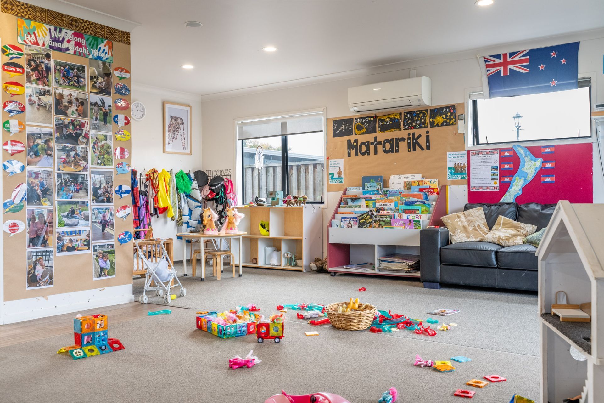 Childcare room with toys scattered on the floor, posters and artwork on the walls, and a couch.