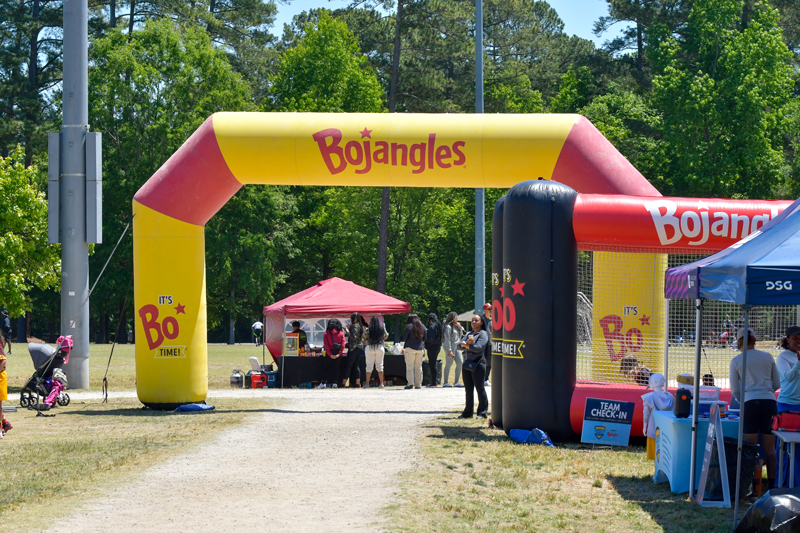 Bojangles event arch with people and tents at an outdoor event