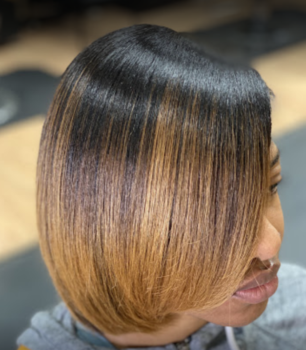 Woman with a bob haircut, black fading to caramel brown, indoors.