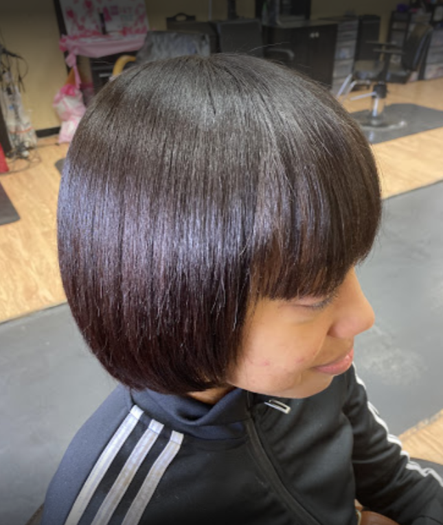 Person with a dark bob haircut, wearing a black jacket, in a salon.