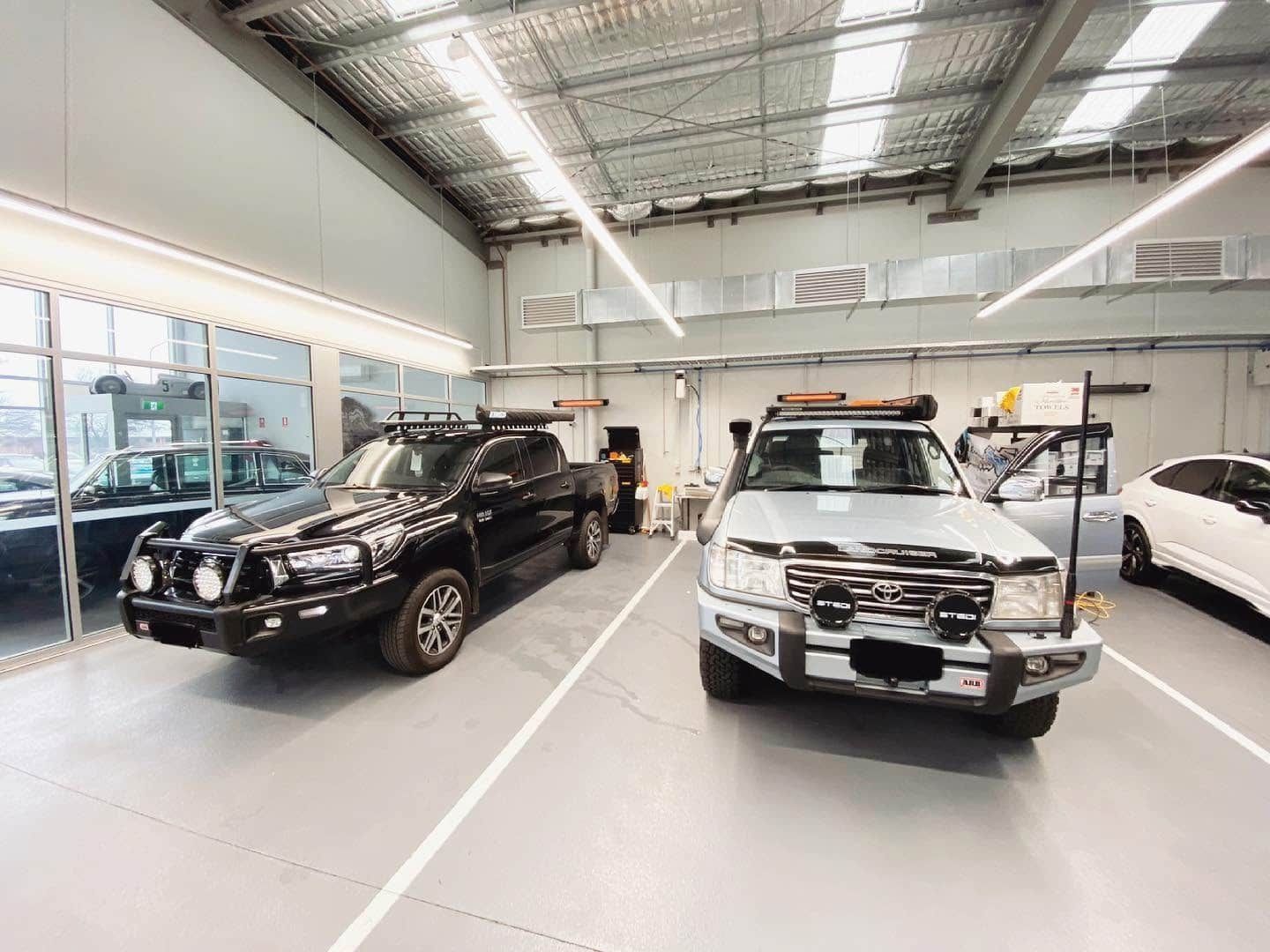 Indoor Car Showroom with Black and White Su vs Parked Under Bright Skylights — Diamond Window Tints in Phillip, ACT