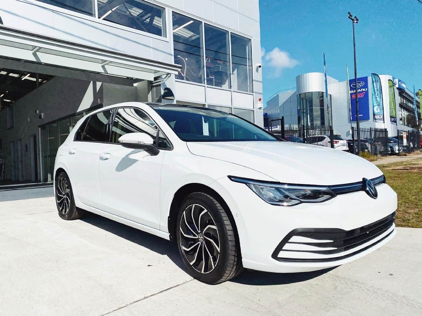 White Volkswagen Hatchback Parked Outside a Modern Building — Diamond Window Tints in Phillip, ACT