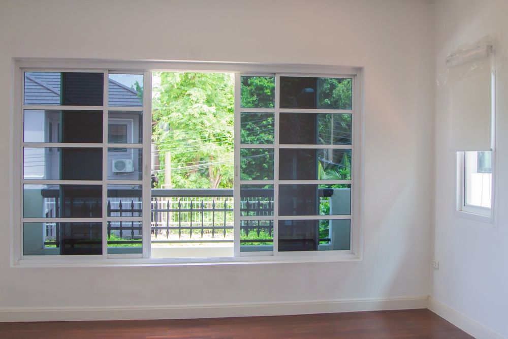 An Empty Room With a Sliding Glass Door Leading to a Balcony — Diamond Tints In Phillip, ACT