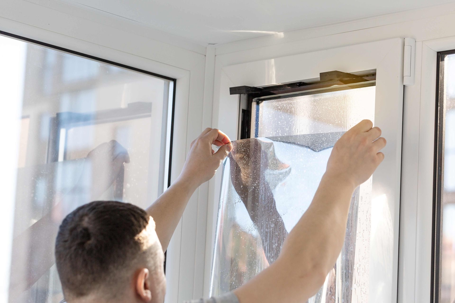 A Man is Installing a Window Film on a Window — Diamond Tints In Phillip, ACT