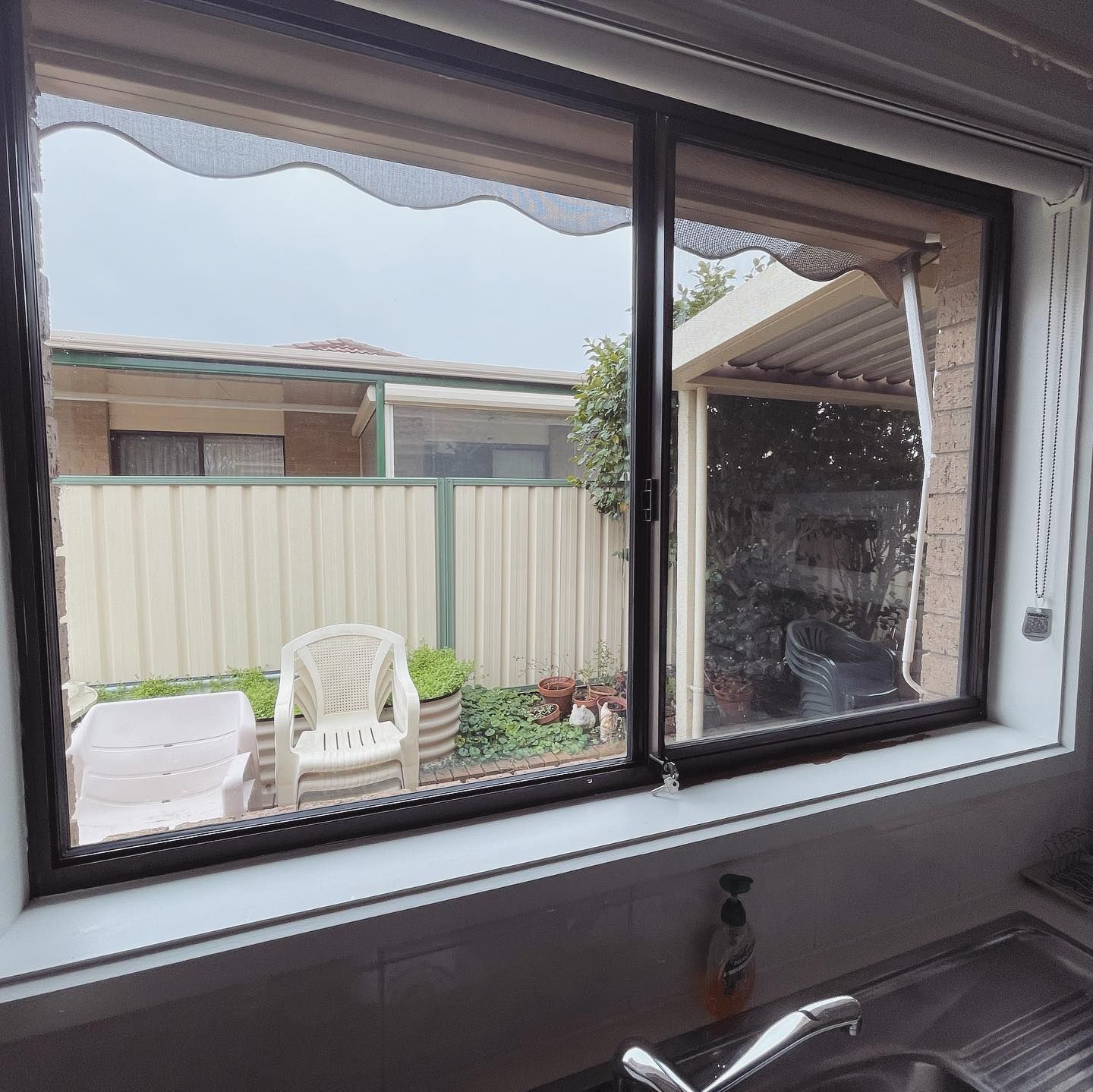 A Kitchen Window With a View of a Fence and Chairs — Diamond Tints In Phillip, ACT