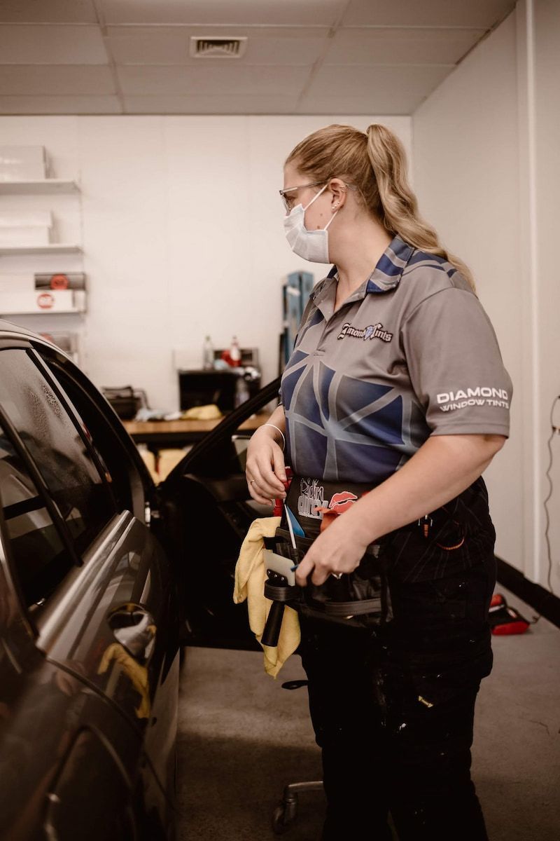 Mechanic in Gray Uniform and Mask Stands Beside a Black Car — Diamond Window Tints in Phillip, ACT