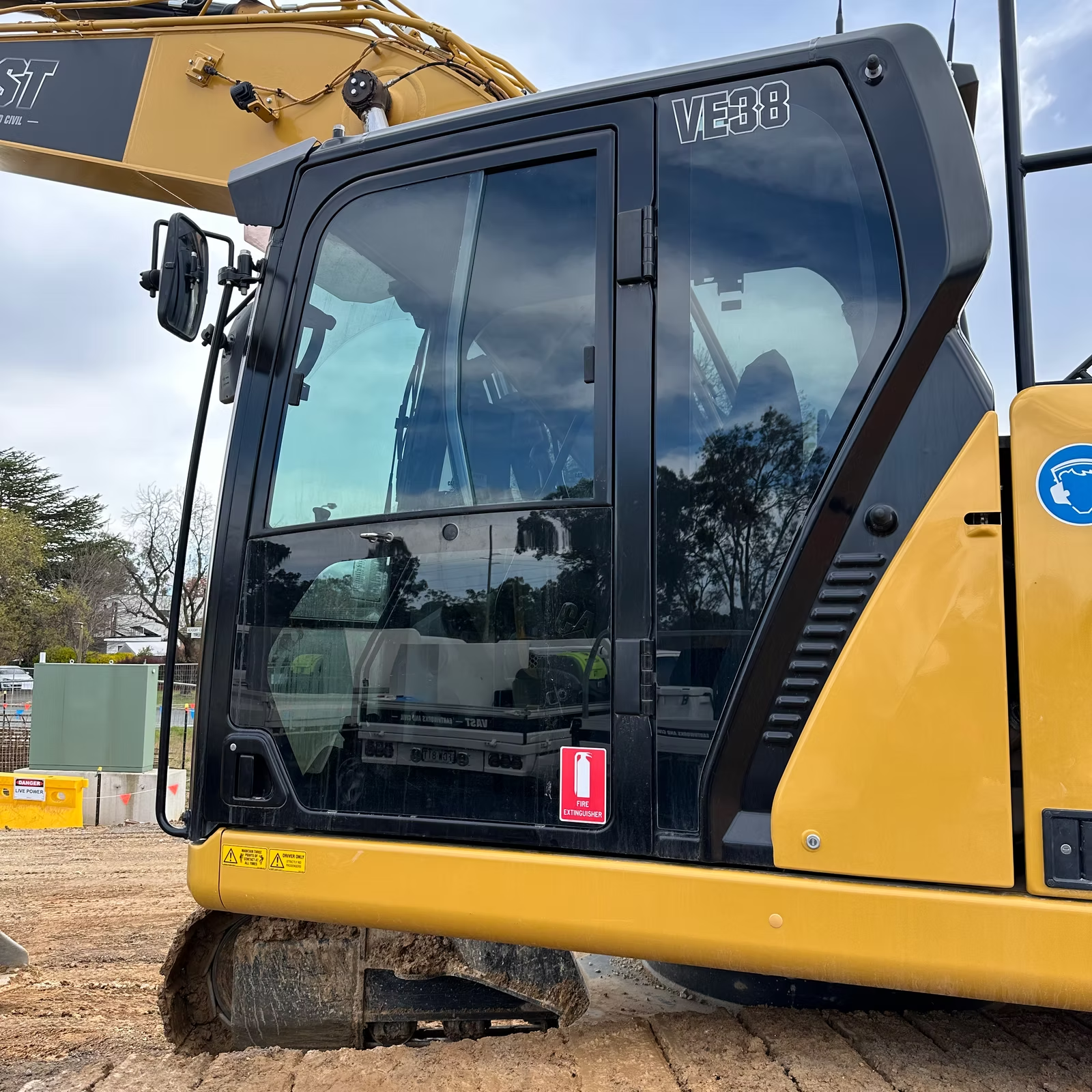 A Yellow and Black Excavator is Parked on a Dirt Road — Diamond Tints In Phillip, ACT