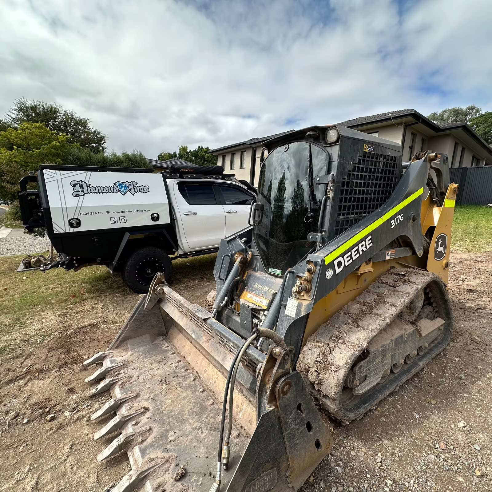 A Bulldozer is Parked Next to a Truck in Front of a House — Diamond Tints In Phillip, ACT