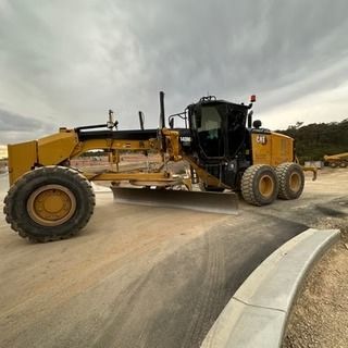 A Yellow Tractor is Driving Down a Dirt Road — Diamond Tints In Phillip, ACT