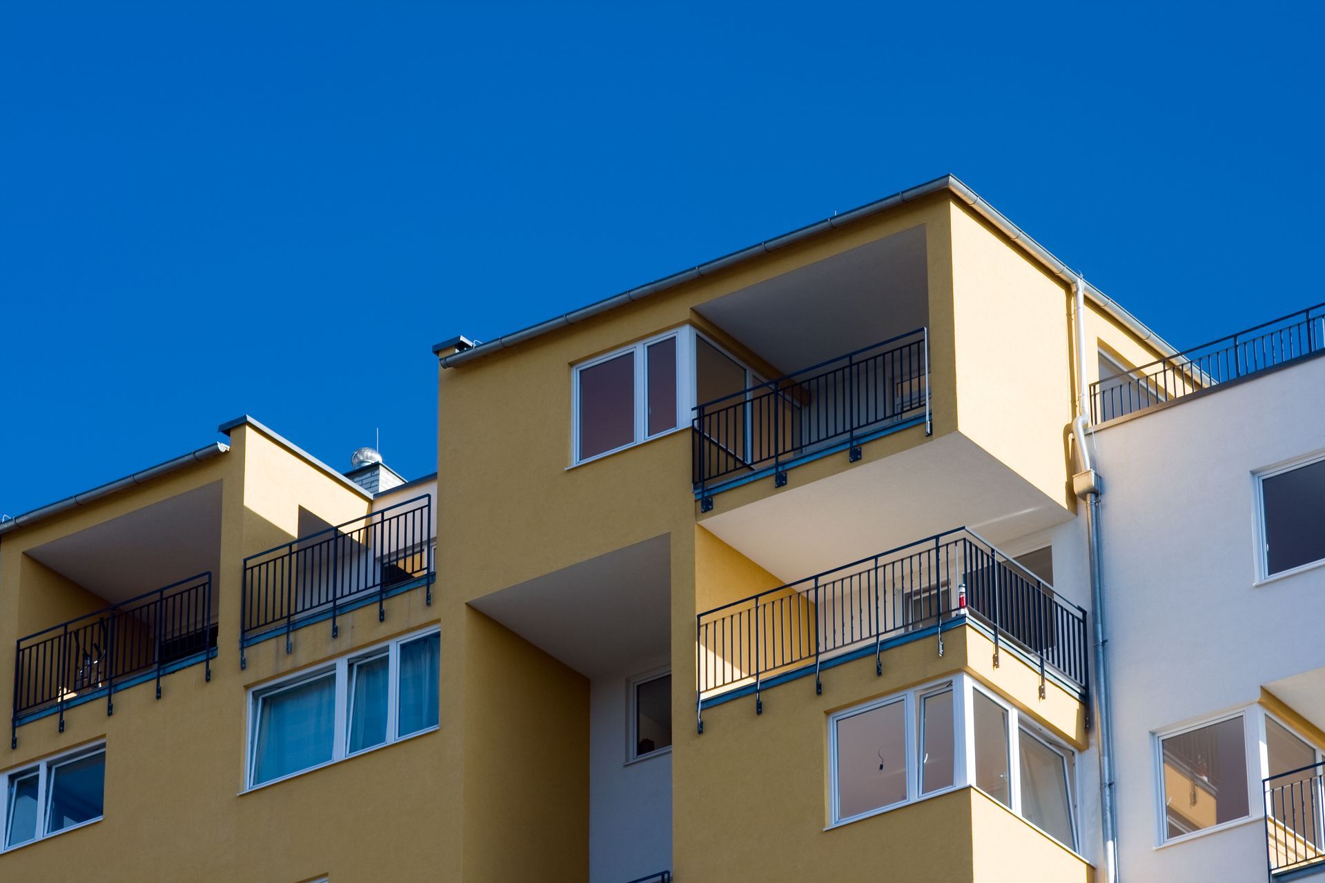 A Block of yellow apartments with balcony railings and tinted windows— Diamond Tints In Phillip, ACT
