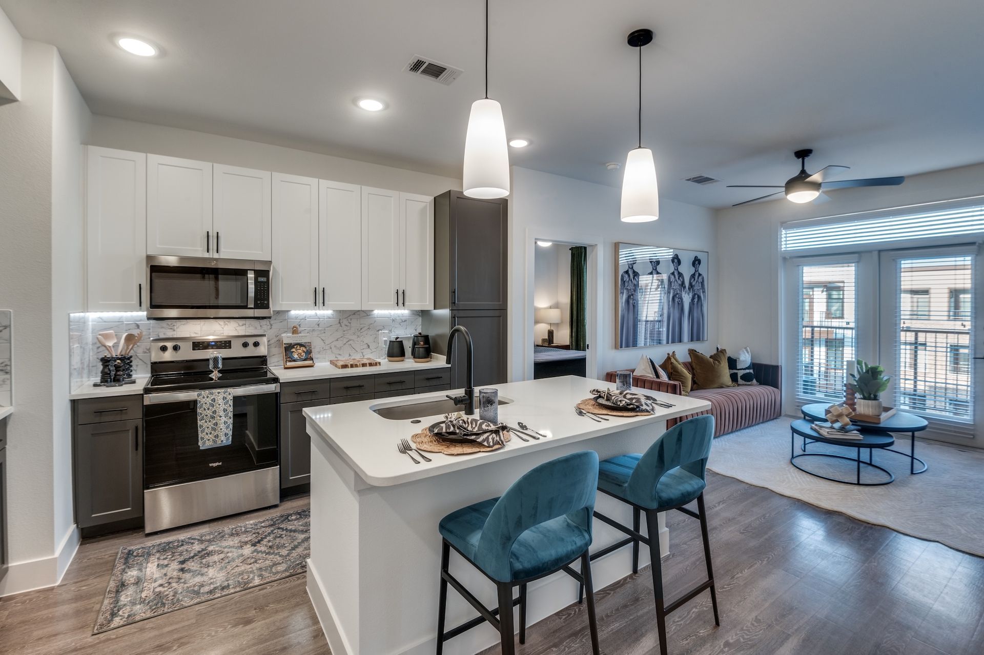 Modern open-concept kitchen and living area with white cabinets, island seating, and gray-blue accents.