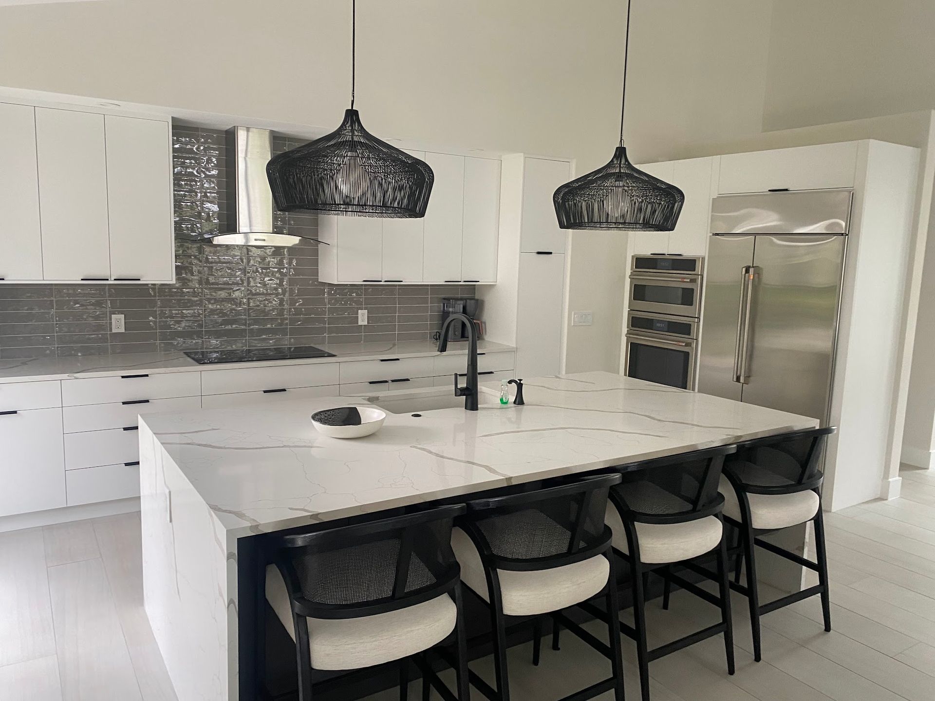 A kitchen with white cabinets , stainless steel appliances , and a large island.
