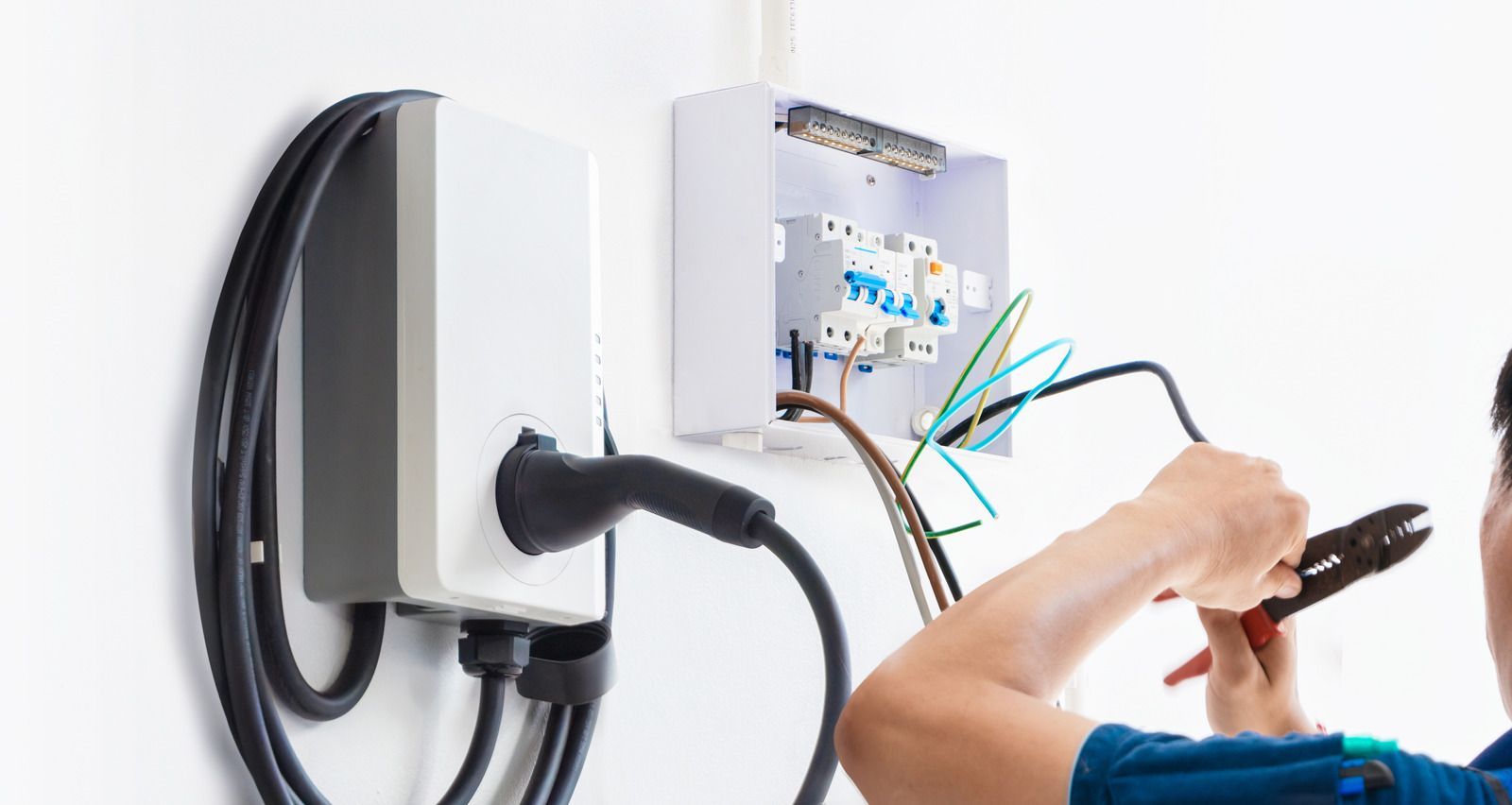 A man is working on an electrical box on a wall.