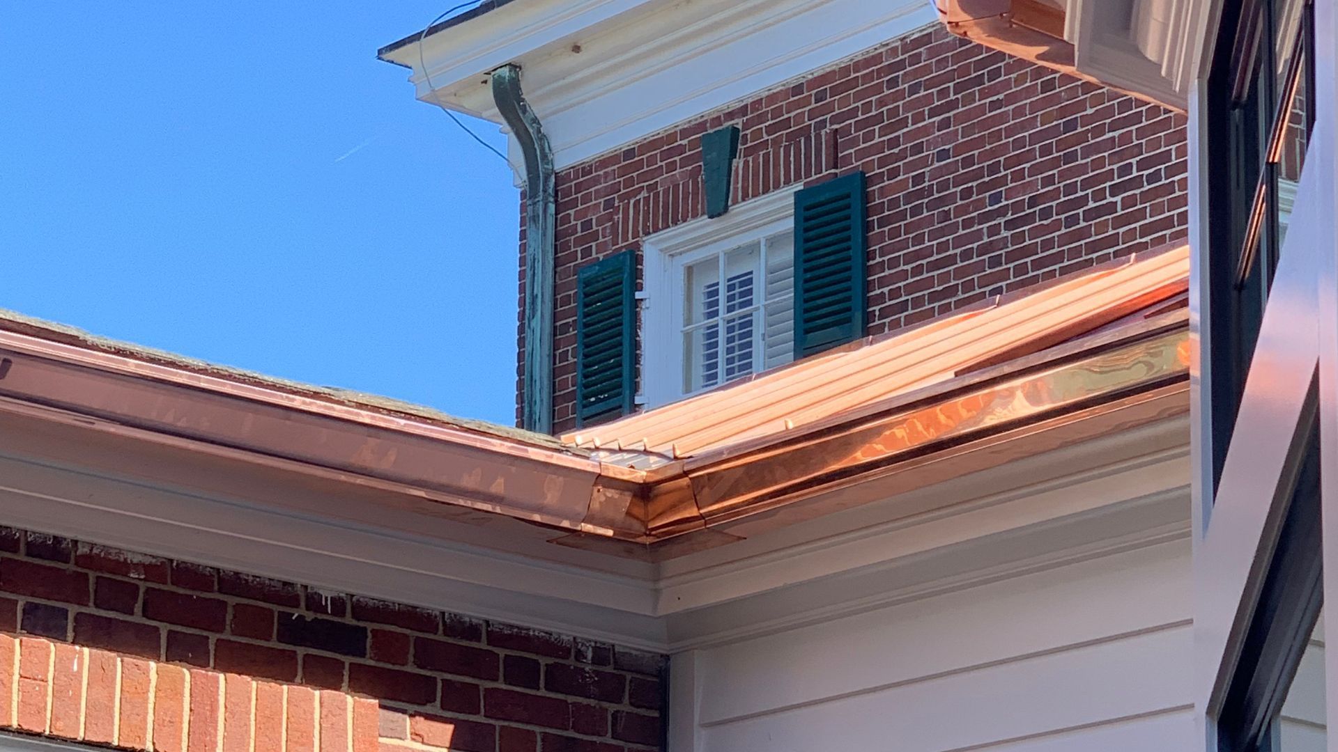 A professional worker wearing gloves standing on a ladder and cleaning the roof gutter