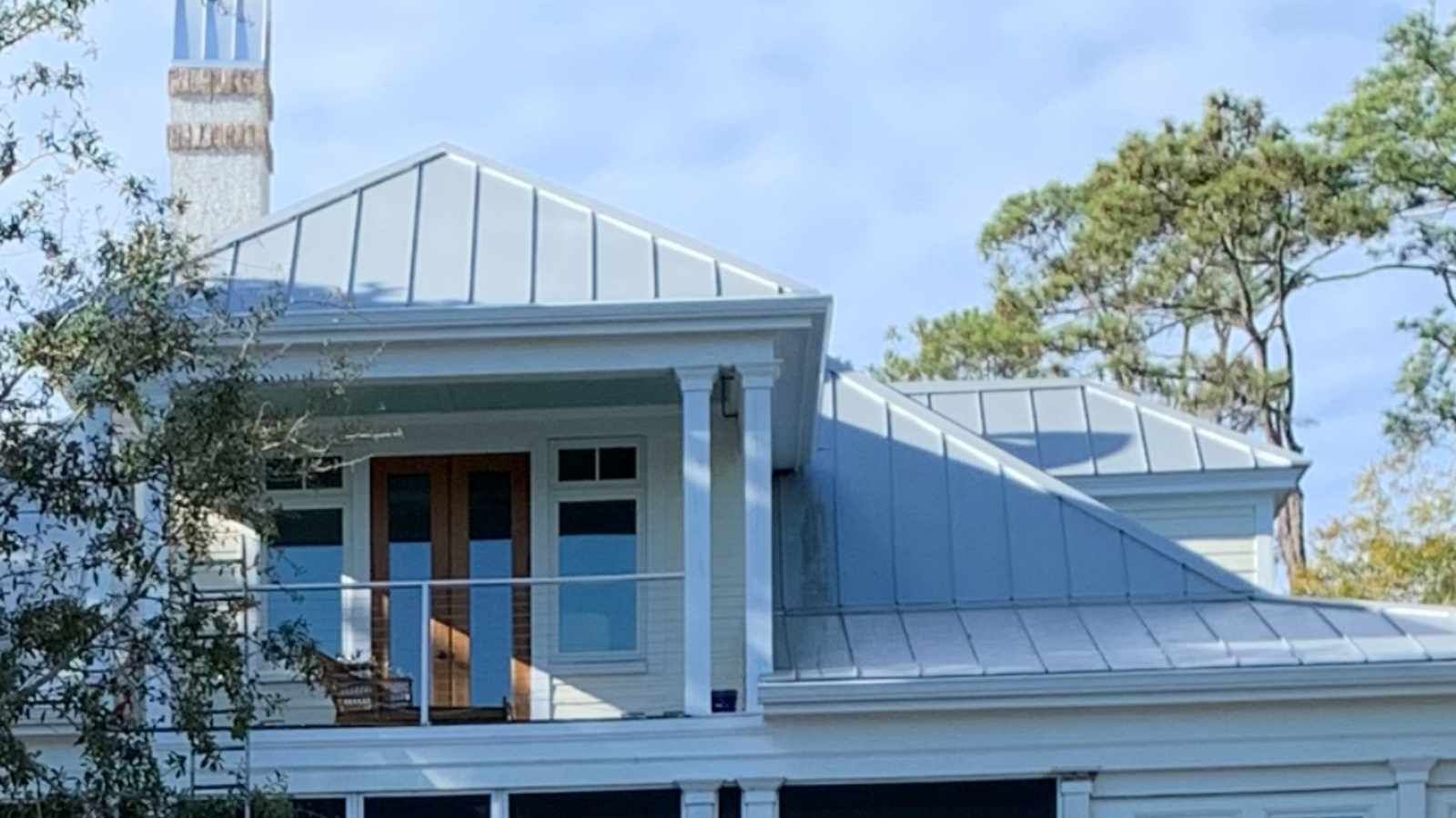 A white house with a metal roof and a chimney.