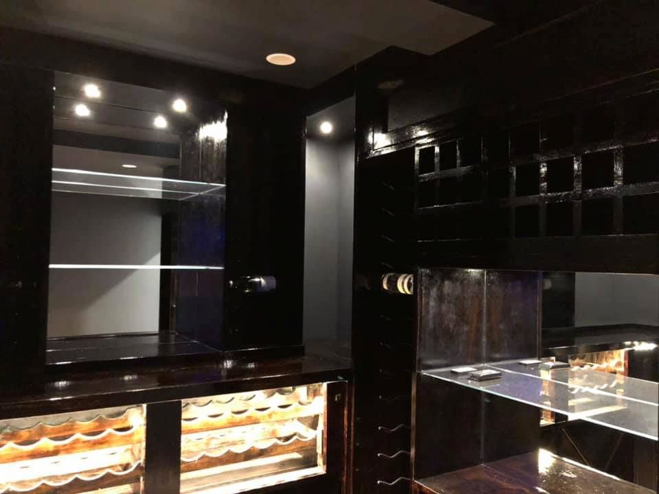 A Modern, Dark-themed Wet Bar With Black Cabinetry, Glass Shelving, Recessed Lighting — Technik Electrical in Renwick, NSW