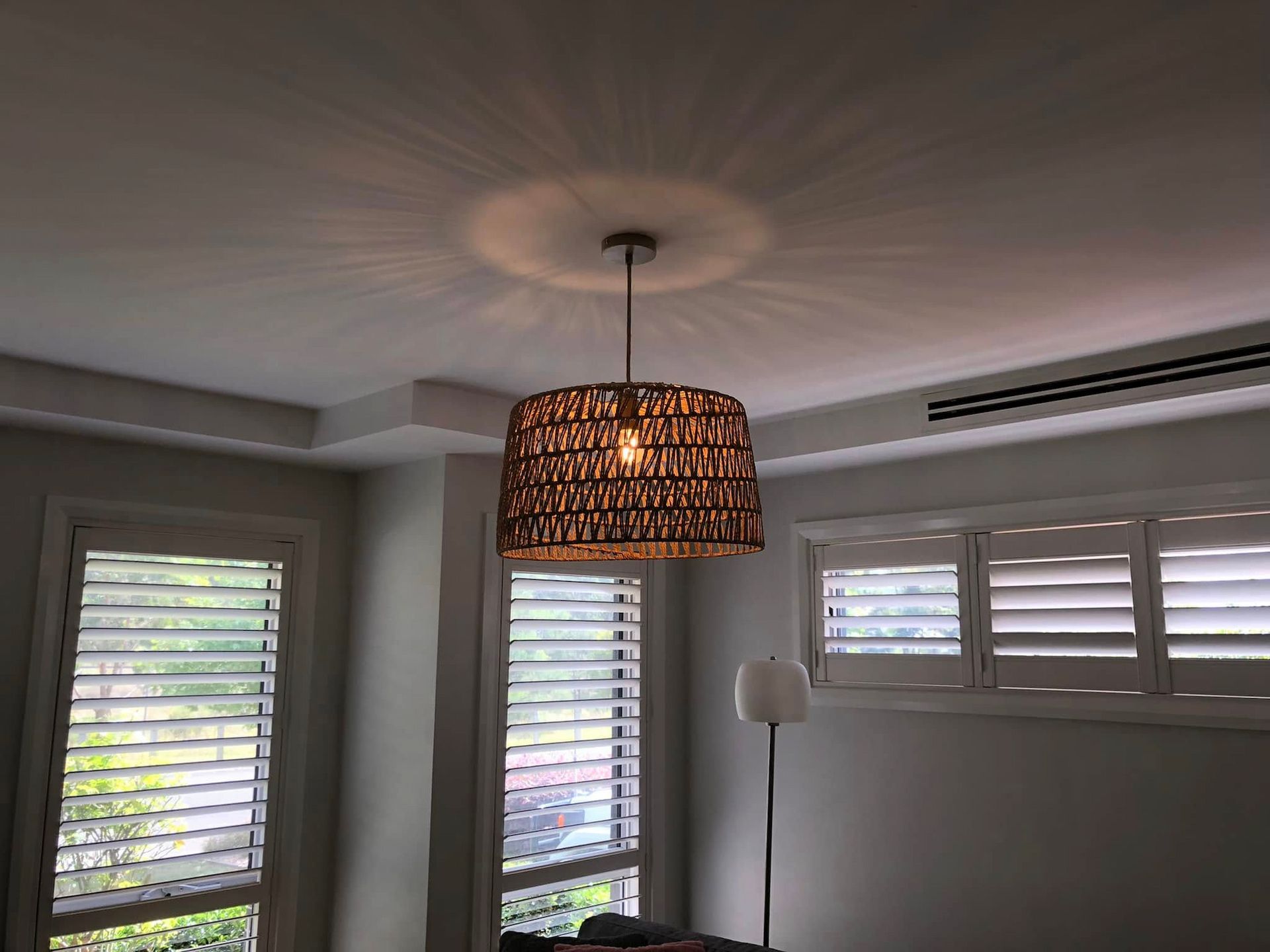 Living room with a wicker pendant light, white blinds, and a floor lamp by the window. — Technik Electrical in Bundanoon, NSW