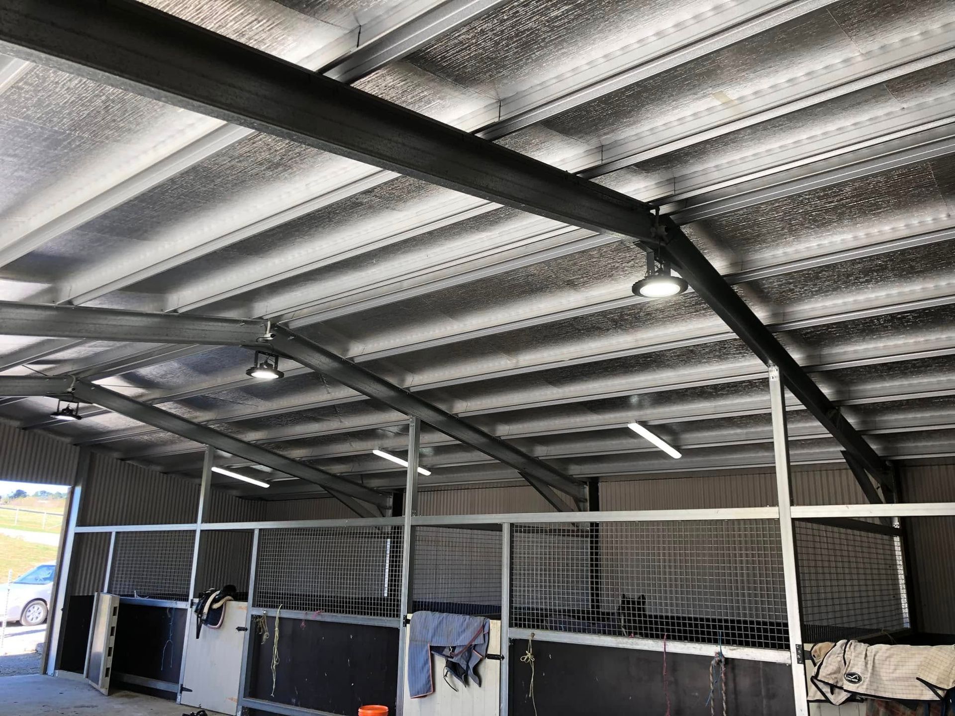 Covered livestock pens with metal roof and railings inside a barn-like shed — Technik Electrical in Renwick, NSW