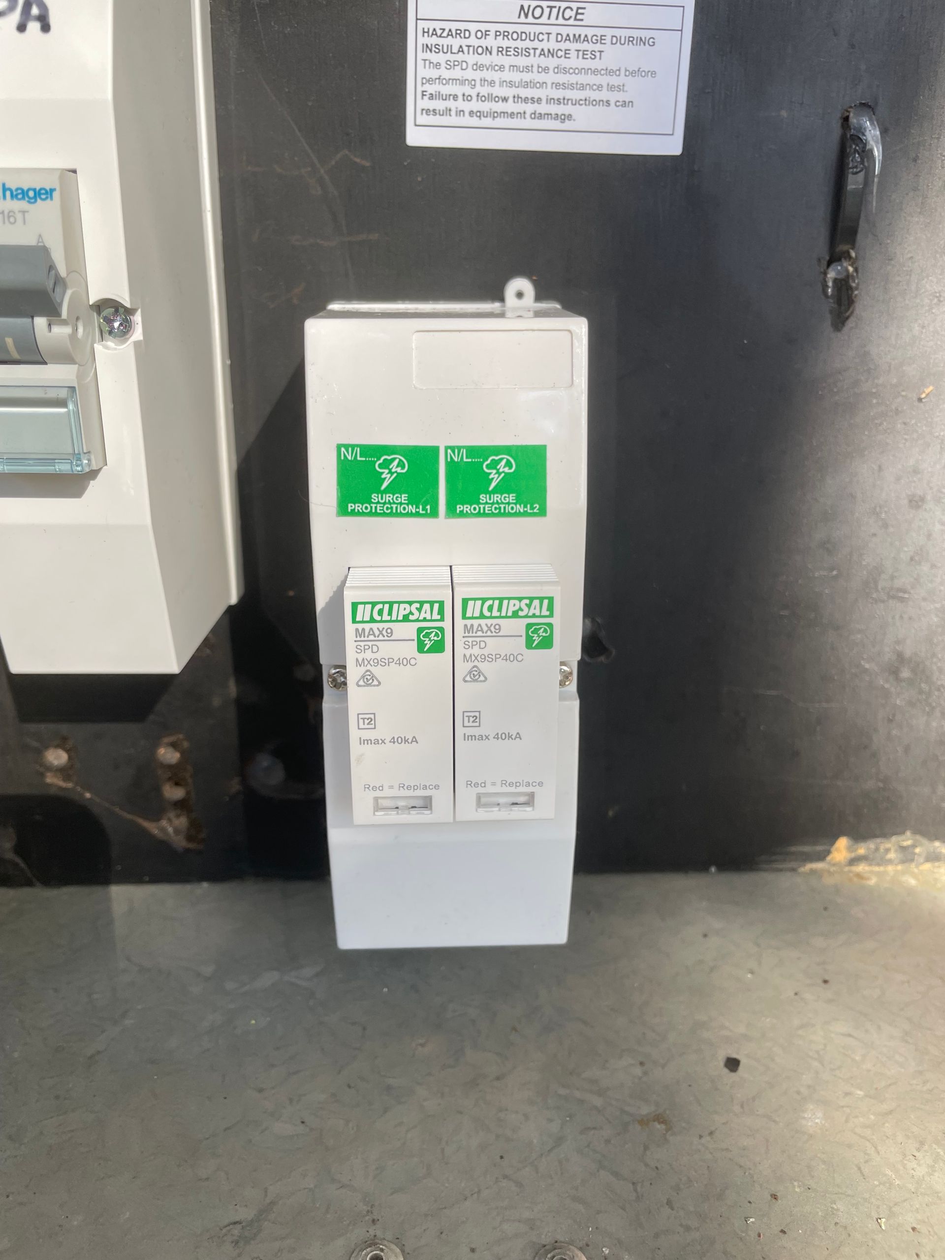 White electrical breaker box mounted on a dark wall next to a blue meter panel. — Technik Electrical in Renwick, NSW