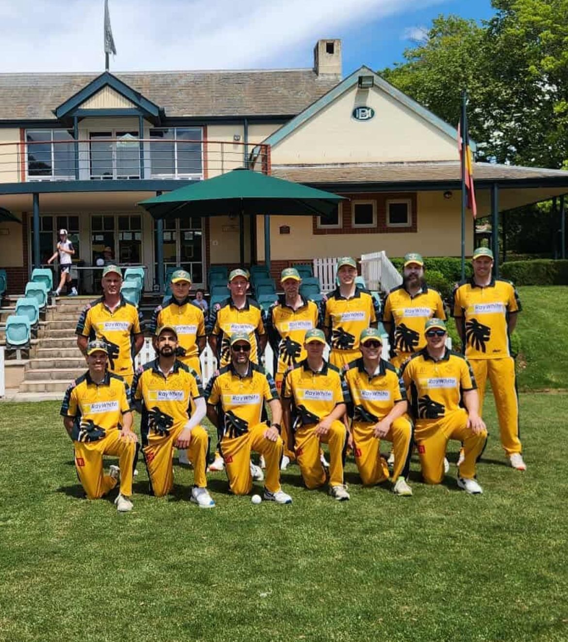 Cricket Team in Yellow Uniforms Posing in Front of a Building — Technik Electrical in Renwick, NSW