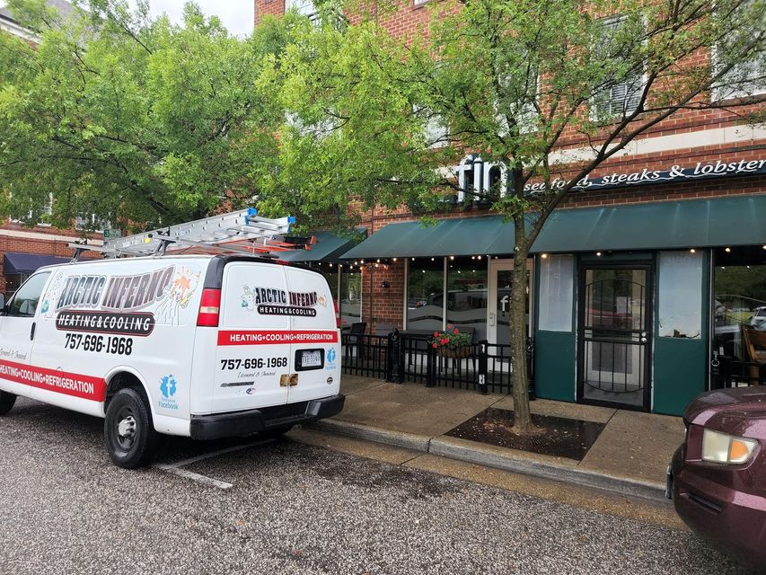 Van parked near restaurant, ladder on roof. Restaurant has green awning, outdoor seating, brick facade.