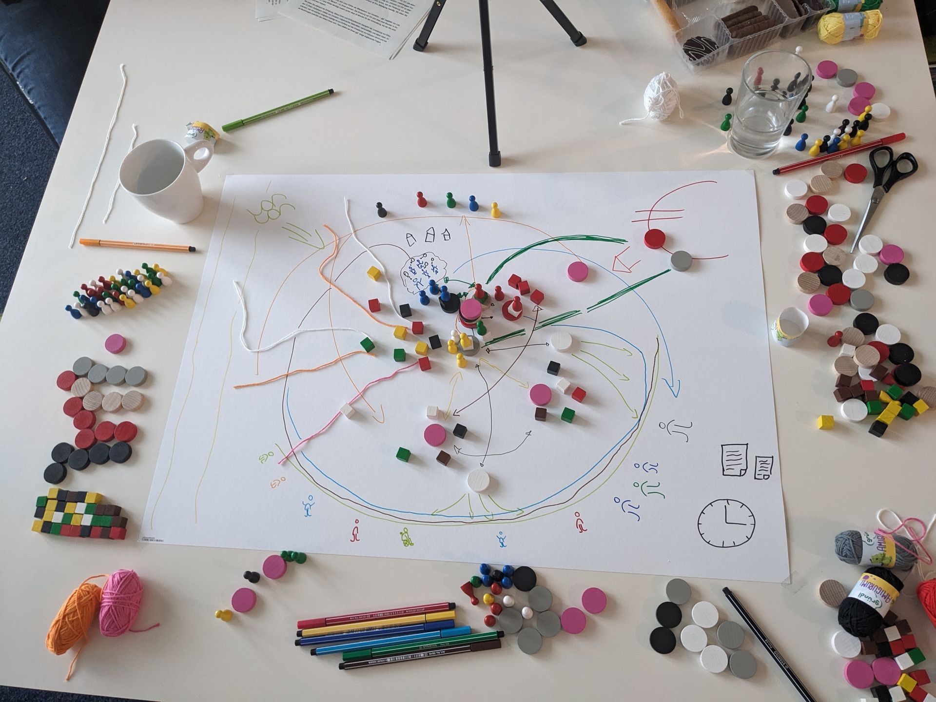 Ein Bild mit ganz vielen verschieden Spielfiguren, Fäden und Zeichnungen drauf.