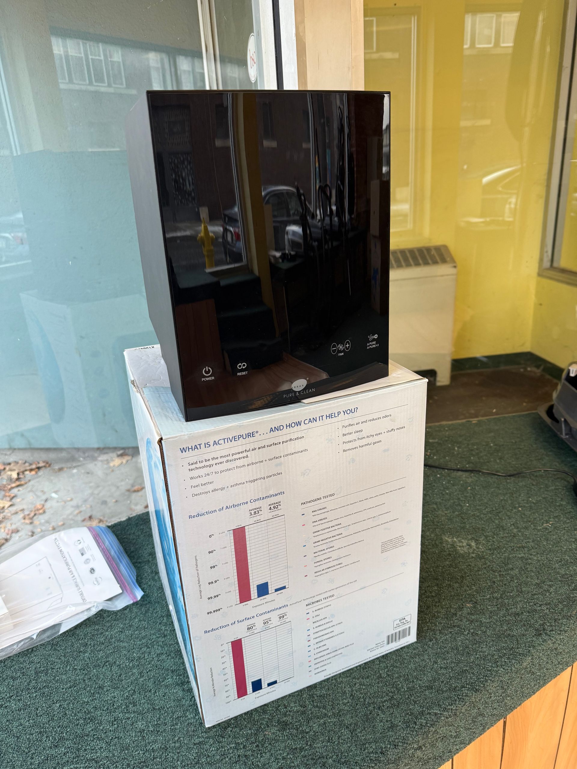 A tall, black, rectangular device sits atop a white cardboard box covered in printed charts and data.