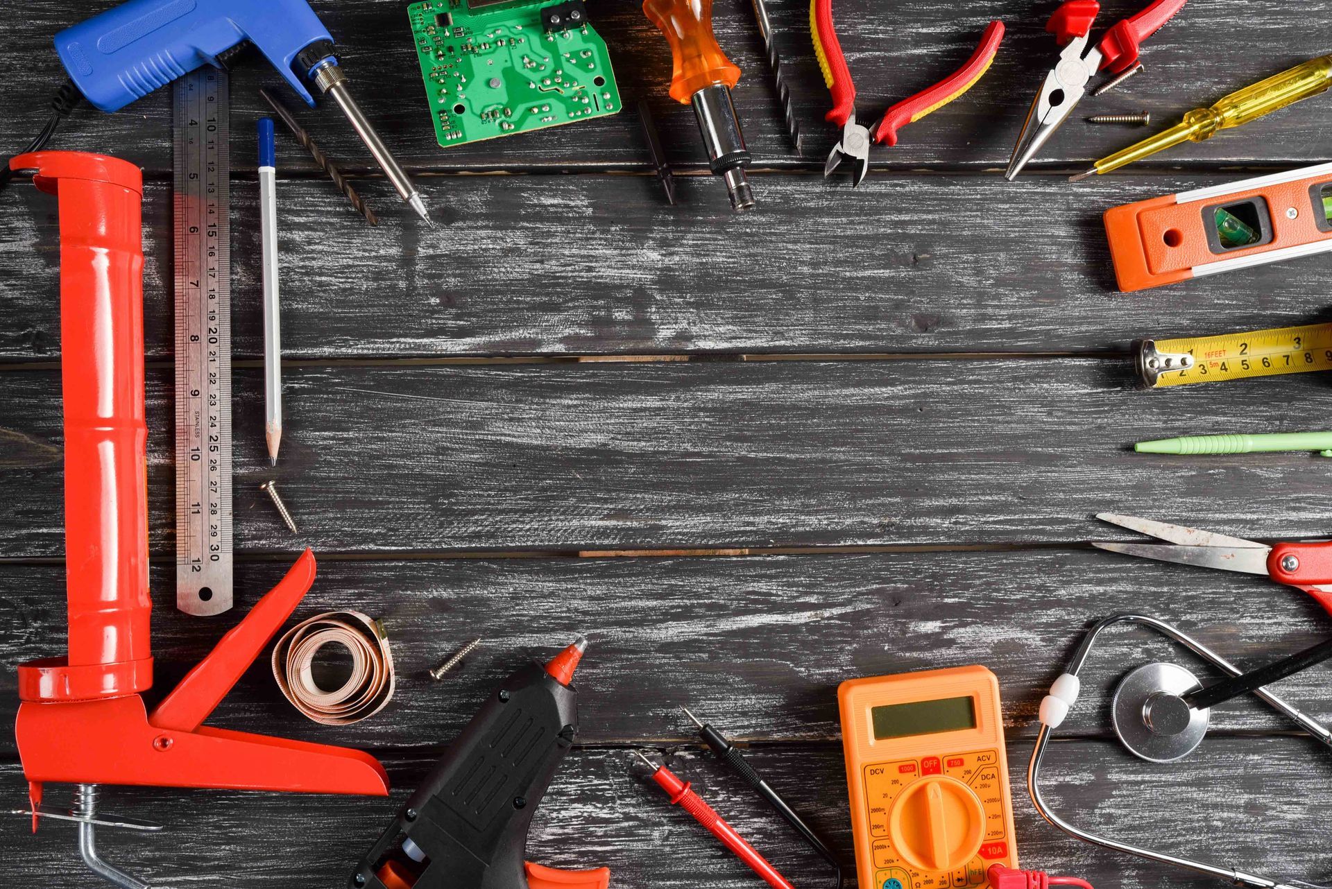 Assorted tools and measuring devices arranged around a dark wooden workbench frame