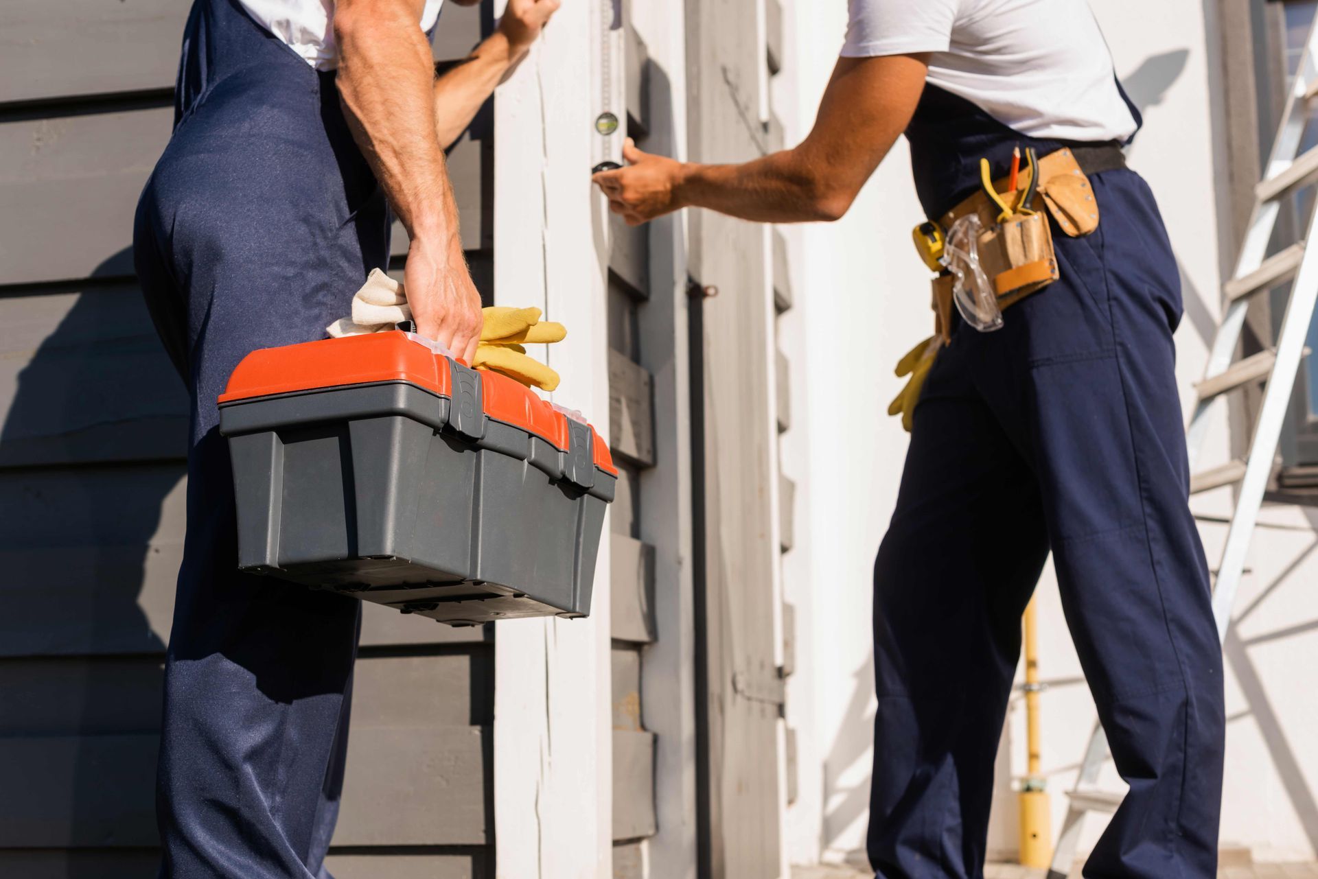 Two workers carrying tools through a doorway during home repair work