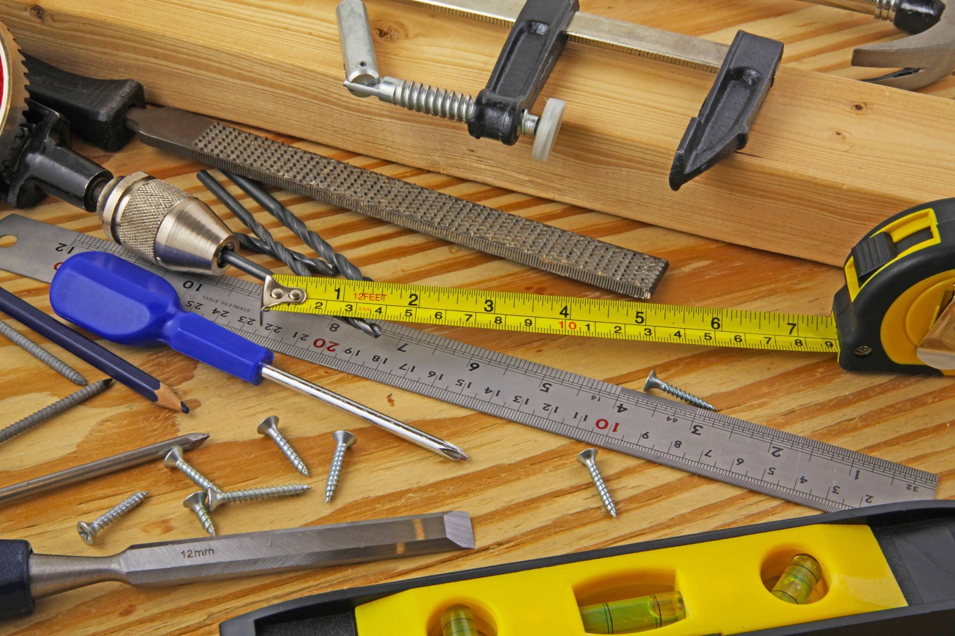 Assorted hand tools, screws, and a tape measure spread across a wooden workbench.